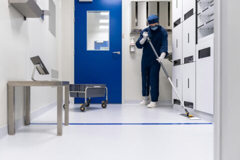 A professional cleaner from Mindful Cleaning Services in Morris County, NJ, meticulously deep cleaning a floor while wearing protective gear.