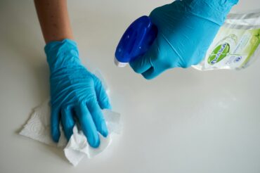 Close-up of a Mindful Cleaning Services professional spraying a non-toxic cleaning solution and wiping a surface with a microfiber cloth.